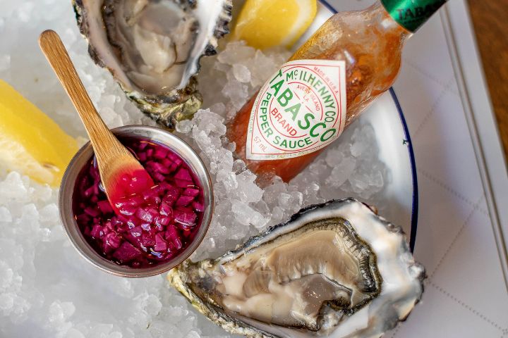 a bowl of ice filled with fresh seafood and a bottle of tabasco pepper sauce